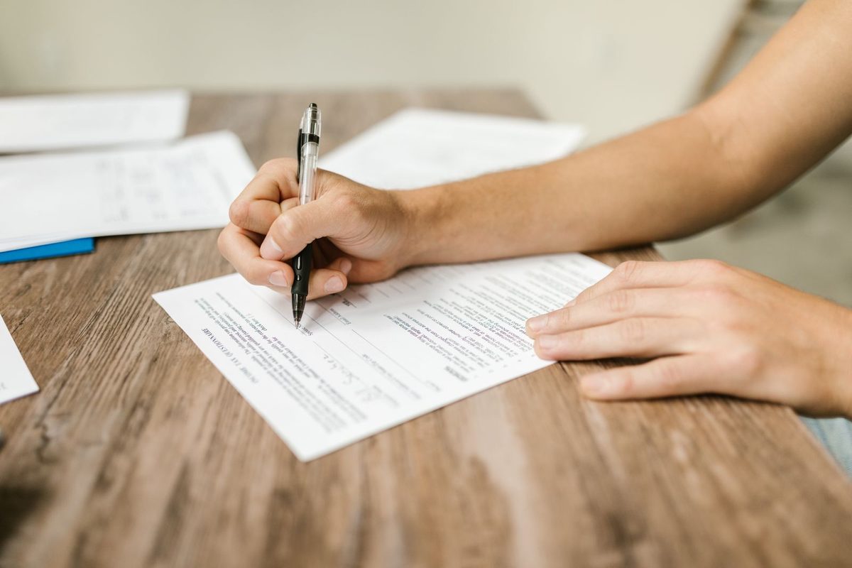 Close-up van een hand die met een pen een formulier invult